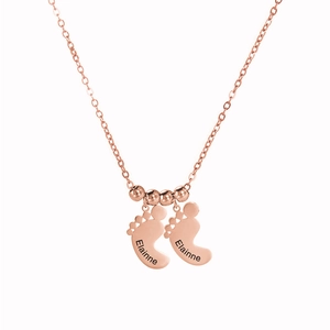 Detail van roségouden ketting met babyvoetjes hangers en kleine gouden kralen