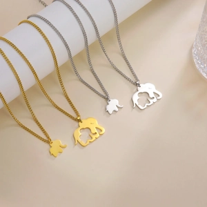 Polished 18K gold and silver elephant pendant necklaces on a minimalist display stand