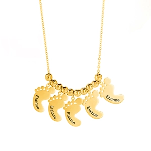 Detailopname van gepersonaliseerde gouden babyvoetjes hangers met aangepaste naamgravure