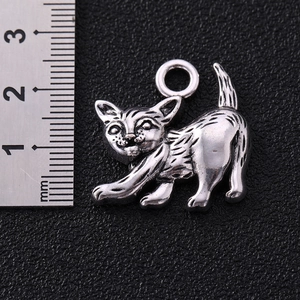Antique silver cat charm for DIY jewelry with 25mm measurement scale on dark background