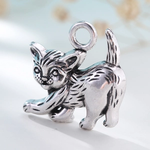 Macro detail of antique silver cat charm with vintage metal texture and hanging loop