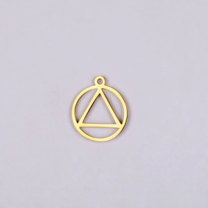 Vue macro d'un pendentif géométrique en acier doré avec cercle et triangle évidés