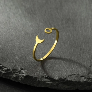 Detail of gold crescent moon and small circle sun ring on a textured dark stone background