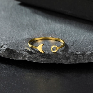 Detailed close-up of golden crescent moon open ring on dark natural stone surface