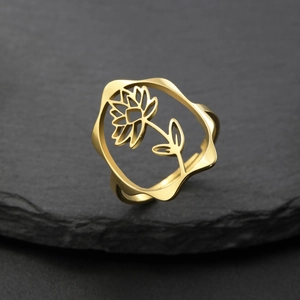 Vue macro d'une bague fleur dorée ajourée avec détails ciselés sur fond de pierre