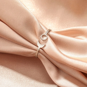 Detailed view of sun and moon open rings nestled in elegant champagne silk fabric