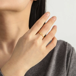 Detail of adjustable gold crescent moon ring worn on finger showing minimalist metal design