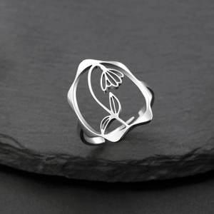 Détail macro d'une bague réglable argentée avec motif floral ajouré sur pierre noire
