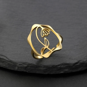 Détail de la bague fleurie ajourée dorée sur pierre noire avec anneau ajustable