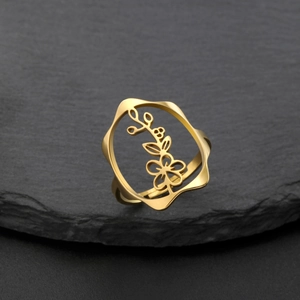 Détail macro de la bague fleur évidée dorée en acier inoxydable sur base de roche noire