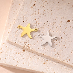 Starfish shaped 18K gold and silver stainless steel charms on stone pedestal