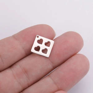 Silver square stainless steel heart cutout pendant shown on fingertips for scale