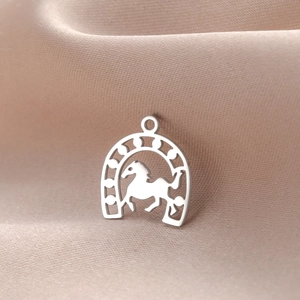 Polished silver horseshoe pendant with running horse silhouette on soft pink satin
