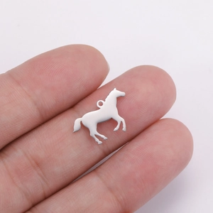 Détail d'un petit pendentif cheval argenté sur un doigt montrant sa taille compacte