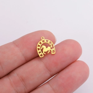 Detailed macro of a 18K gold-plated stainless steel horseshoe pendant with horse carving