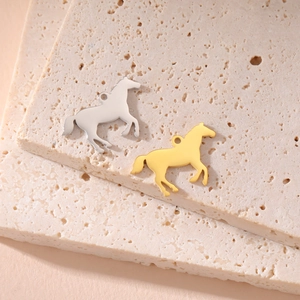 Golden and silver stainless steel horse pendants on warm beige travertine stone