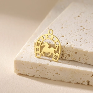 Macro shot of 18K gold plated stainless steel horseshoe pendant on stone background