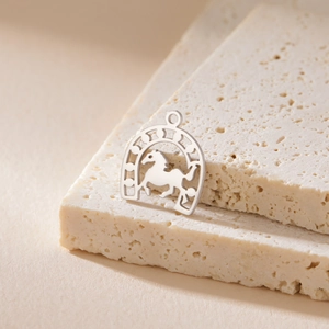 Detailed view of a silver stainless steel horseshoe and running horse pendant on stone