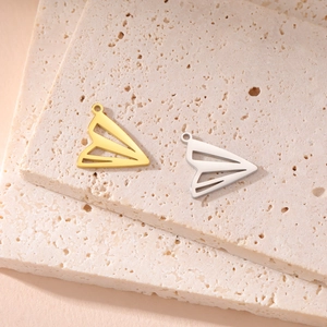 Close-up of gold and silver paper plane pendants on stone tiles, minimalist DIY charms
