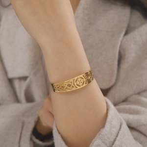 Dettaglio del bracciale vichingo dorato con nodi celtici e trafori indossato al polso