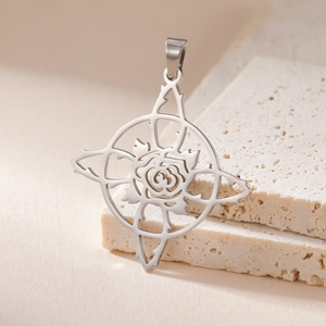 Detailed close-up of a silver stainless steel rose pendant on beige travertine stone