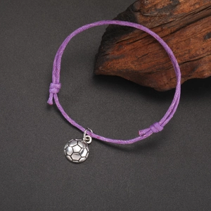 Detailed close-up of a purple braided rope bracelet with a silver soccer ball pendant charm