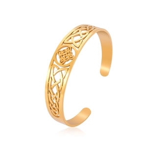 Close-up of golden stainless steel cuff bracelet with Celtic knot and cut-out patterns