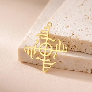 Detailed view of a gold-plated Viking Vegvisir compass charm on a textured stone surface