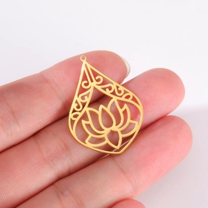 Golden hollow teardrop pendant with lotus design held in hand for size visualization