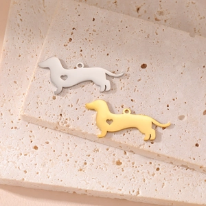Polished 18K gold and silver dachshund pendants with heart cutout on travertine stone