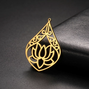 Macro side view of a gold-toned teardrop-shaped lotus flower pendant on a dark texture