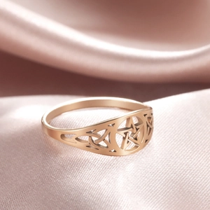 Macro shot of gold hollow pentagram ring with Celtic textures on purple silk fabric