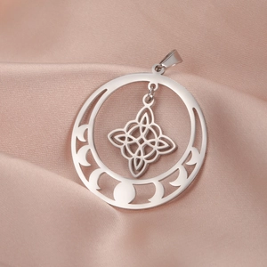Macro view of silver triple moon and witch knot charm on champagne silk fabric