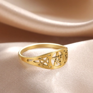 Close-up of golden hollow pentagram ring with Celtic knots on champagne silk