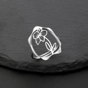 Vue détaillée d'une bague florale creuse en acier argenté poli sur fond de pierre