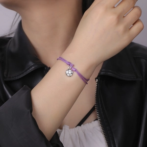 Detail of adjustable purple woven rope bracelet with a silver soccer ball charm on a wrist