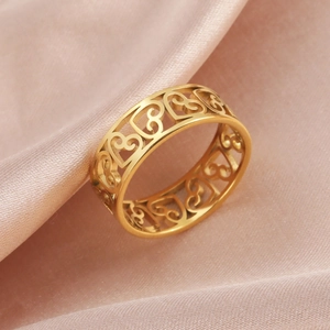 Gros plan d'une bague dorée à motifs cœurs évidés sur tissu satiné rose élégant et chic