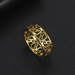 Bague large dorée avec motifs de cœurs évidés sur un fond noir mat élégant et chic