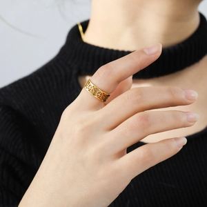 Bague en acier inoxydable doré avec motifs de cœurs évidés sur le doigt d'un mannequin