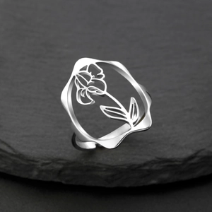 Détail de la bague fleur argentée ajourée avec anneau réglable sur pierre sombre