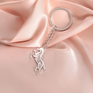 Detailed macro of stainless steel Celtic horse keychain on soft pink satin fabric