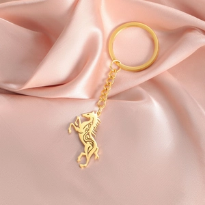 Detail of a golden stainless steel Celtic horse keychain on a pink silk background