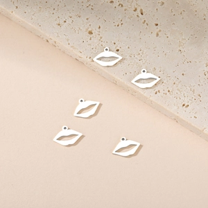 Close-up of five silver lip-shaped hollow charms for DIY jewelry making on stone