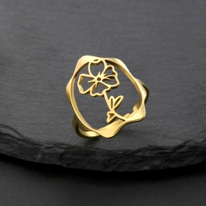 Gros plan d'une bague fleur évidée dorée avec motif floral sur pierre noire