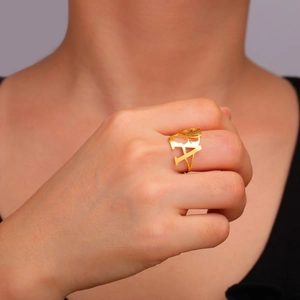 Detail of model wearing a gold hollow letter A ring with a female profile silhouette