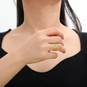 Gros plan d'une bague géométrique dorée avec des lignes en V multicouches au doigt