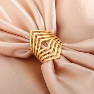 Bague géométrique ajourée en V en acier inoxydable doré sur un élégant tissu en soie champagne