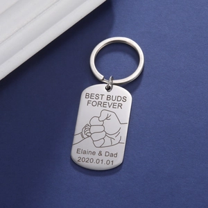 Close-up of laser-engraved titanium steel keychain with fist bump and custom text