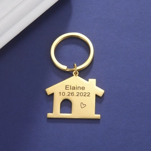 Dettaglio portachiavi a forma di casa dorato con incisione di nome e data