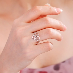 Close-up of silver stainless steel heart ring with Celtic knot design on a finger